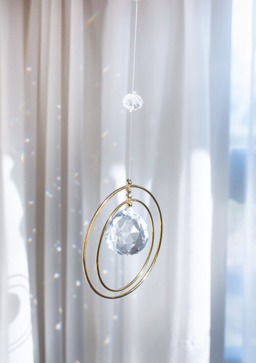 Attrape soleil en cristal - Mandala Attrape soleil cristal, à coté d'une fenêtre avec des arcs en ciel de lumière, DENADDA