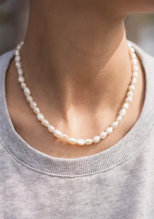 Collier perles d'eau douce blanche autour du cou. Un bijou fait main par Elma de DENADDA.
