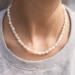 Collier perles d'eau douce blanche autour du cou. Un bijou fait main par Elma de DENADDA.