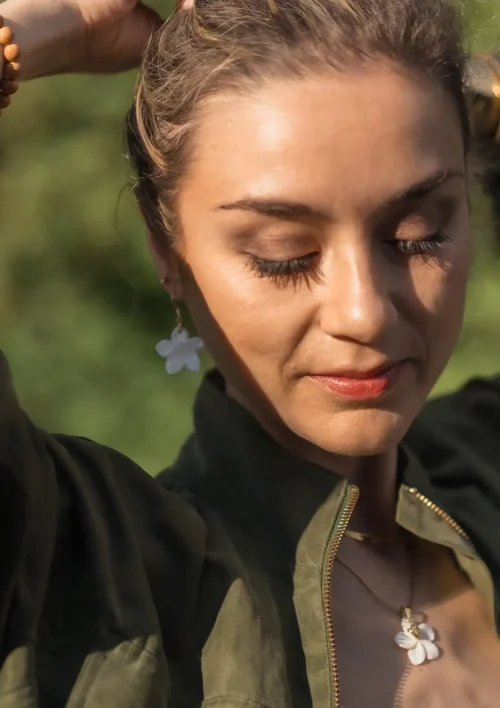 Boucle d'oreille - Fleur de Nacre Femme portant une boucle d'oreille nacre en forme de fleur, un pendentif en nacre et ses bracelets assortis. Des bijoux faits main par DENADDA.