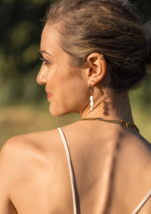 Boucle d'oreille pendante perles d'eau douce - Aura Une femme qui porte une boucle d'oreille pendante en perle d'eau douce. Aura un bijou fait main par DENADDA.
