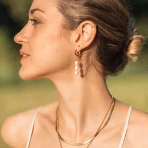 Boucle d'oreille pendante perles d'eau douce portée par une femme. Aura est un bijou fait main de la collection Pure de DENADDA.