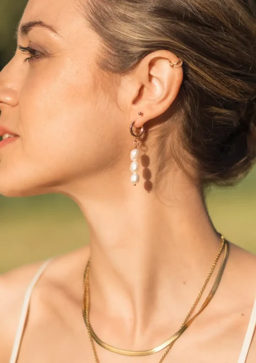 Boucle d'oreille pendante perles d'eau douce - Aura Boucle d'oreille pendante perles d'eau douce portée par une femme. Aura est un bijou fait main de la collection Pure de DENADDA.