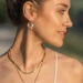 Une femme porte une boucle d'oreille en perle de pierre de lave blanche. Un bijou élégant fait main par DENADDA.