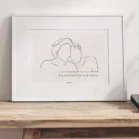 Cadre personnalisé couple dessin minimaliste avec citation sur un fond uni posé sur une table en bois. Dessin style line art réalisé d'un seul trait par Denadda. Idéal pour une décoration intérieur minimaliste. Cadeau de couple original et unique.