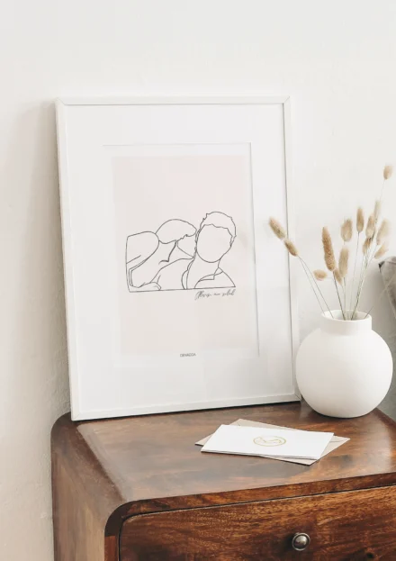 Tableau personnalisé couple dessin minimaliste sur fond uni posé sur un meuble en bois avec vase décoratif. Un portrait de couple dessiné au trait par Denadda dans le style line art.